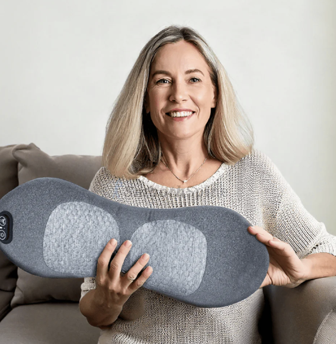A woman holding the SmoothSpine Triple Fusion Massager, showing its size